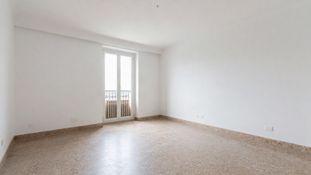 Salón vacío de un piso pequeño en España con suelo de terrazo y balcón